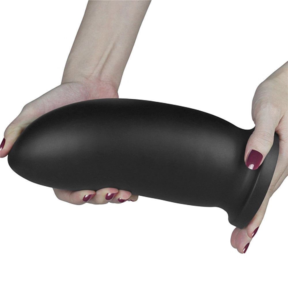 9 King Sized Anal Bomber svart PVC analtoy från Chambers of Love hållen med båda händerna som visar flexibilitet och storlek – 23 cm längd, 8,5 cm diameter, 961 gram vikt