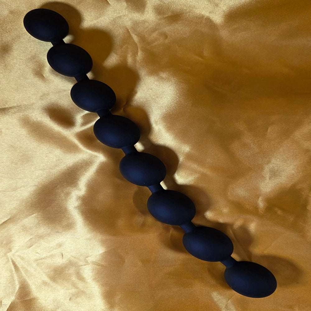 Kedja med 8 äggformade analkulor i storlek Smal, svarta, på guld färgad  bakgrund från Chambers of Love