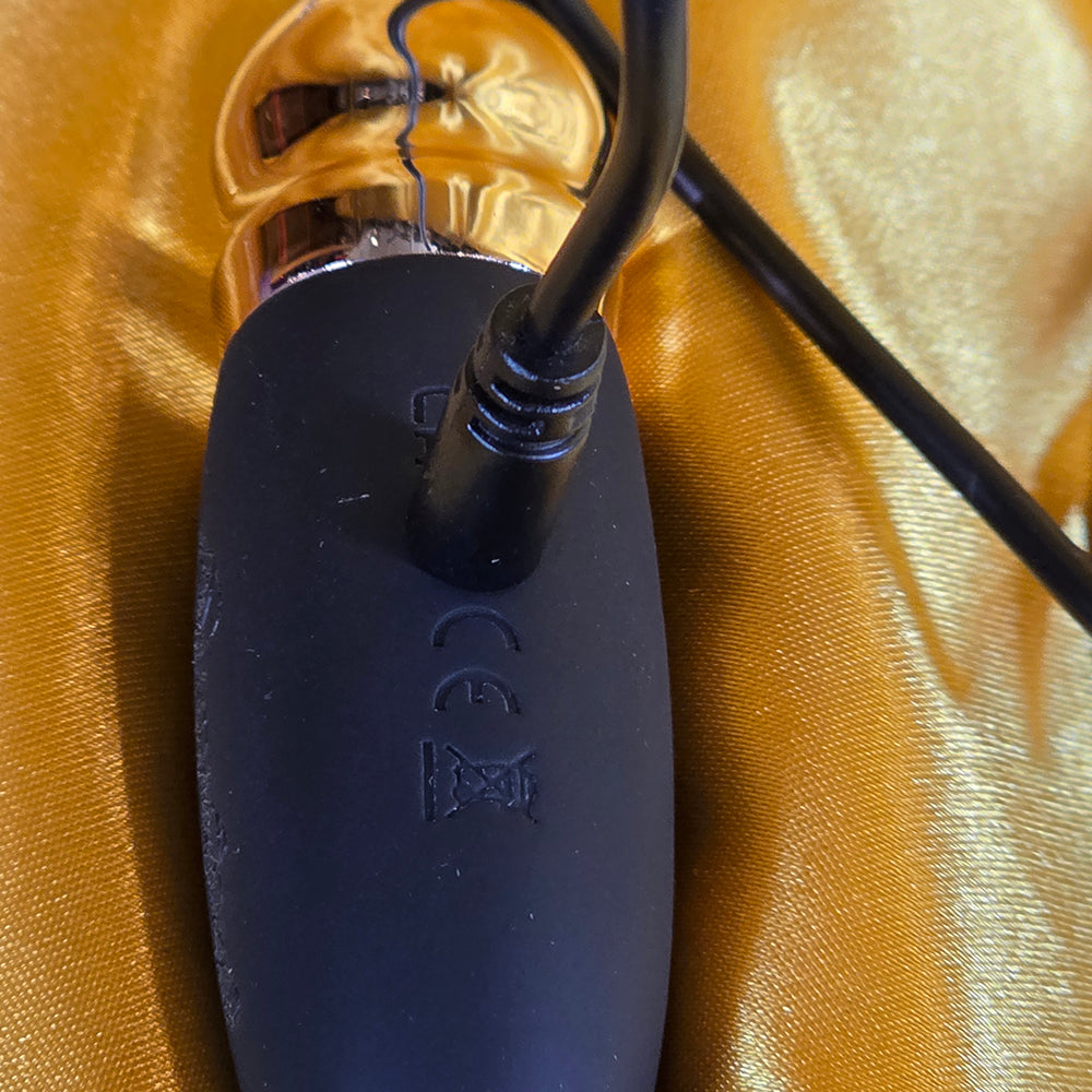 Betty Bullet guldsmycke vibrator med ansluten laddkabel på guldbakgrund – Chambers of Love