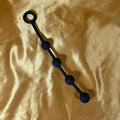 Fyra Kulors Anal Beads i liten storlek med fyra stegrande silikonkulor och säkerhetsring i änden, fotograferade på guldsidenbakgrund. Från Chambers of Love.