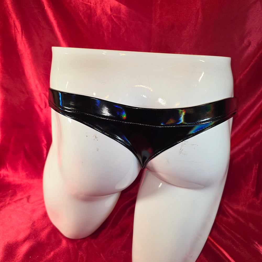 Hologram PVC String – Herr i svart holografisk PVC, bakifrån på mannekäng. Tight T-string med hologram-glans och smal passform.