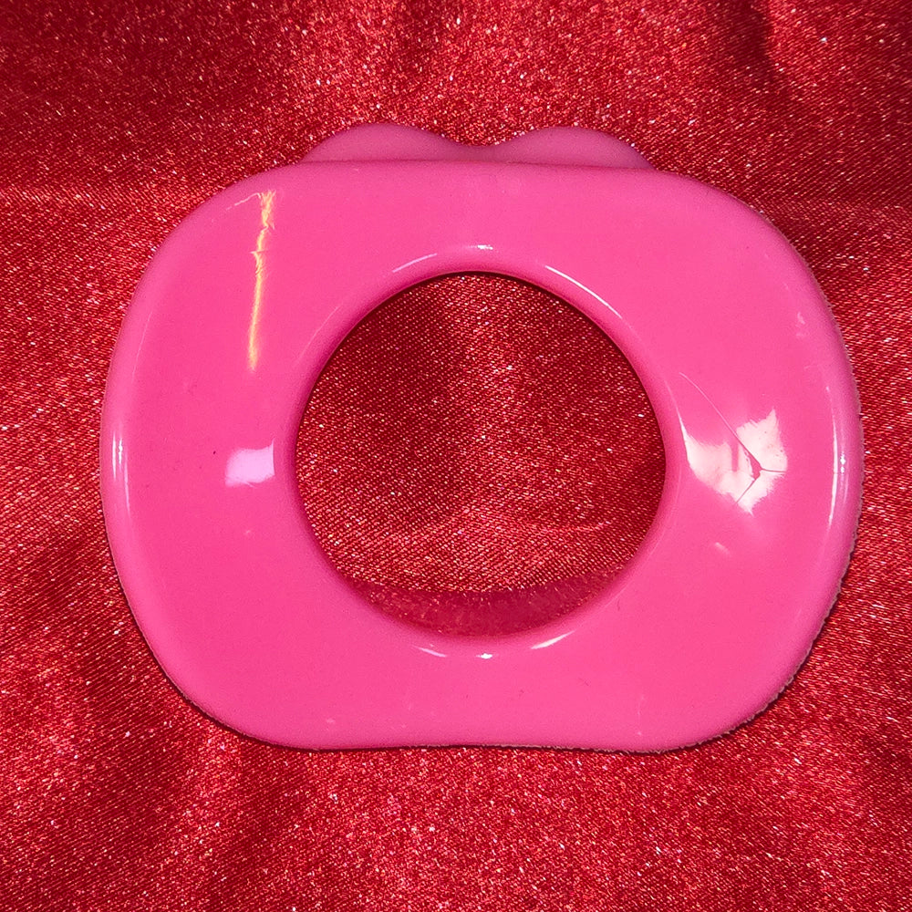 Öppen Mun Gag i rosa silikon, baksida  på röd glitterbakgrund. O-ring gag för BDSM och kinky lek från Chambers of Love.