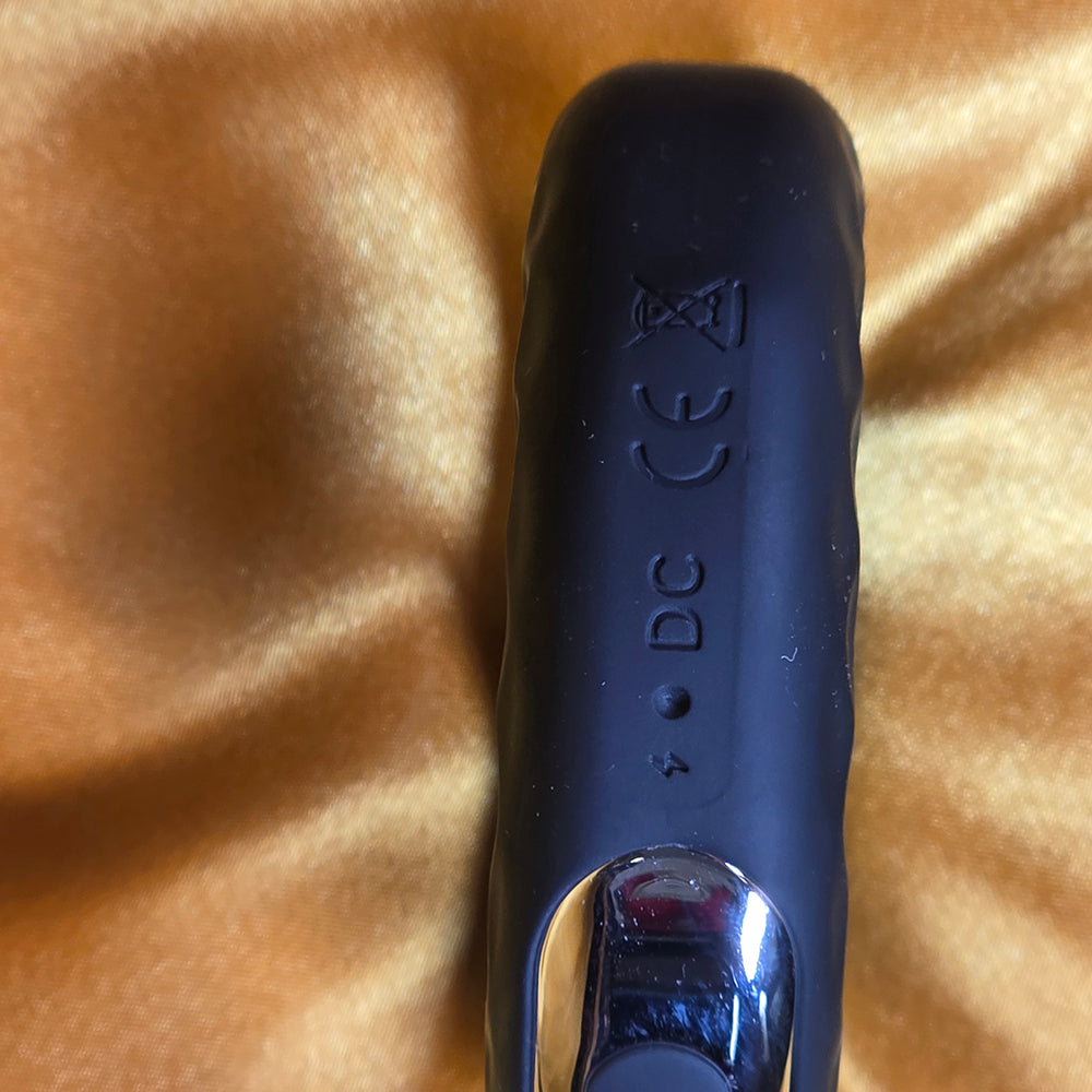Närbild på laddhål och DC-port på penisring med 10 vibrationer för anslutning av USB-laddare på guldfärgad bakgrund från Chambers of Love