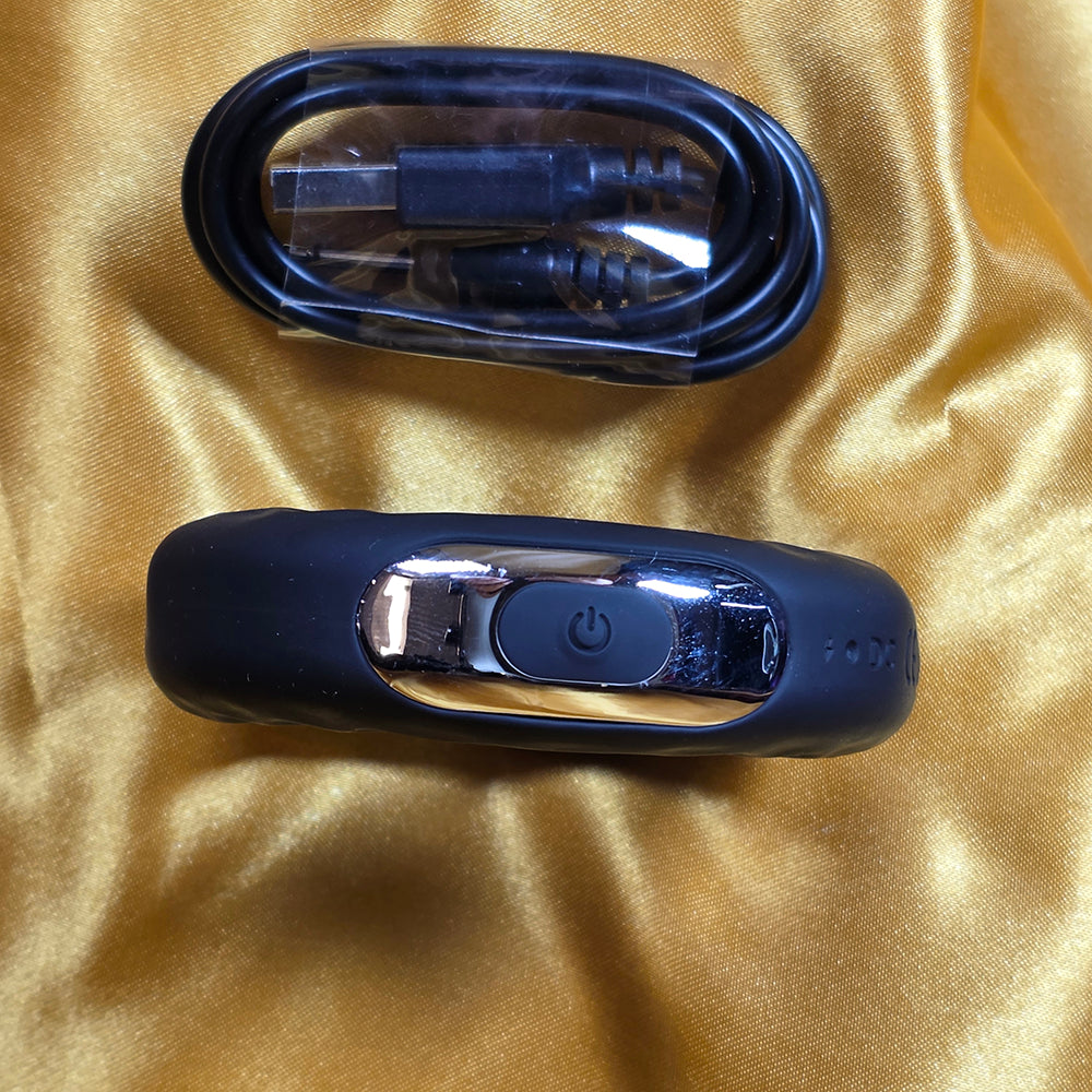 Penisring med 10 vibrationslägen och USB-laddkabel på guld färgad  bakgrund från Chambers of Love